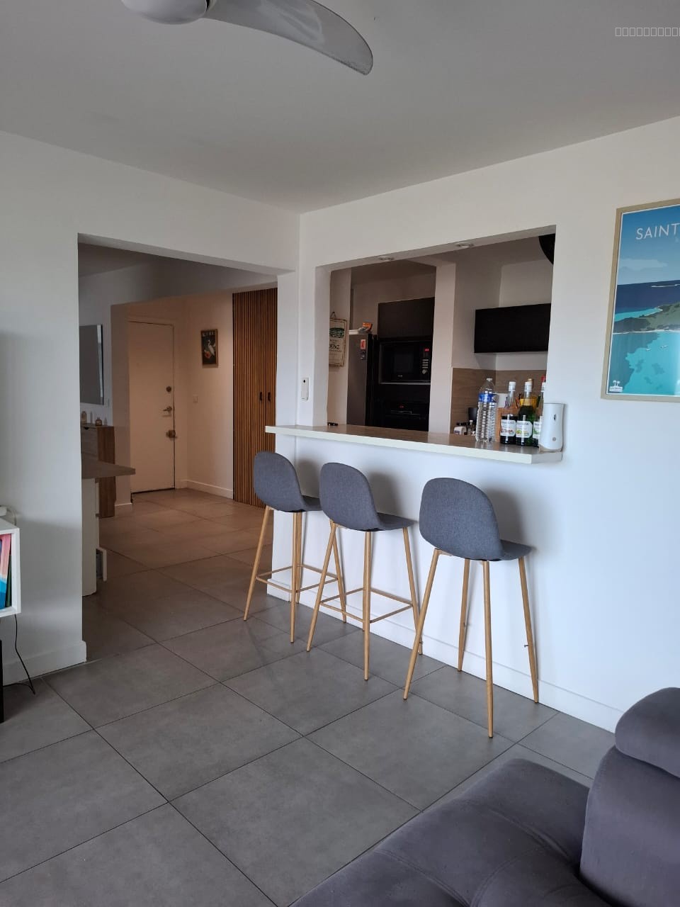 Appartement à vendre à Saint martin : bar avec trois tabourets gris devant la cuisine
