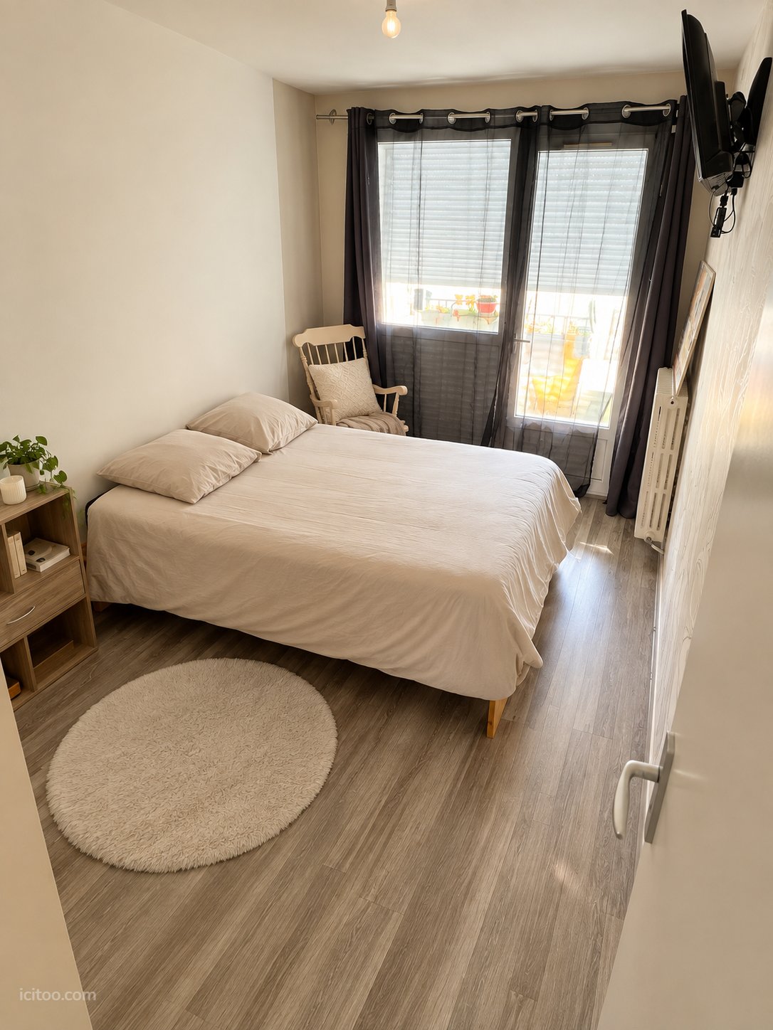 Appartement à vendre à Tarbes : chambre avec lit double, table de chevet et fenêtre avec rideaux