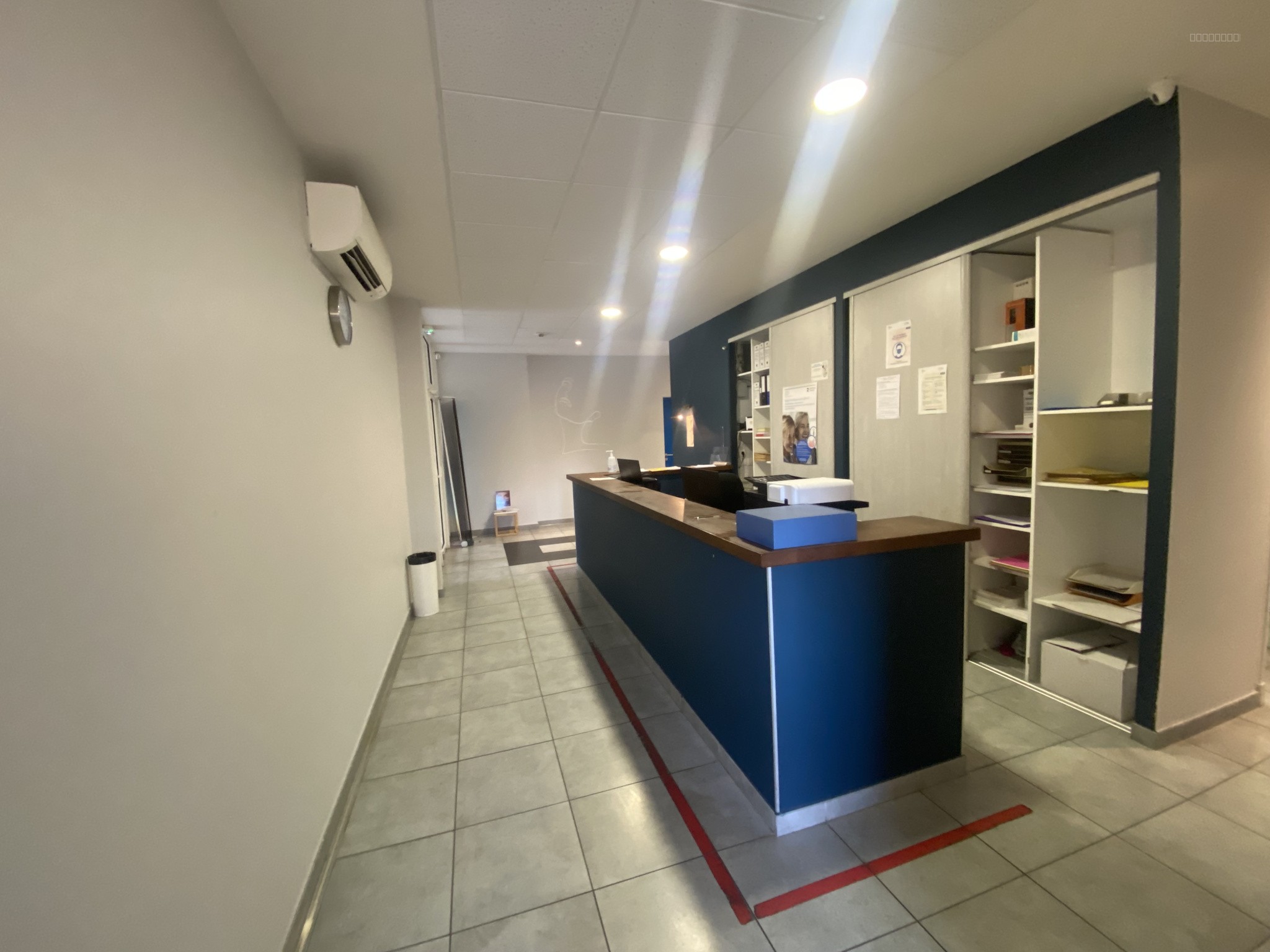 Bien à vendre à Carcassonne : vue de l'entrée avec comptoir d'accueil, étagères murales et sol carrelé