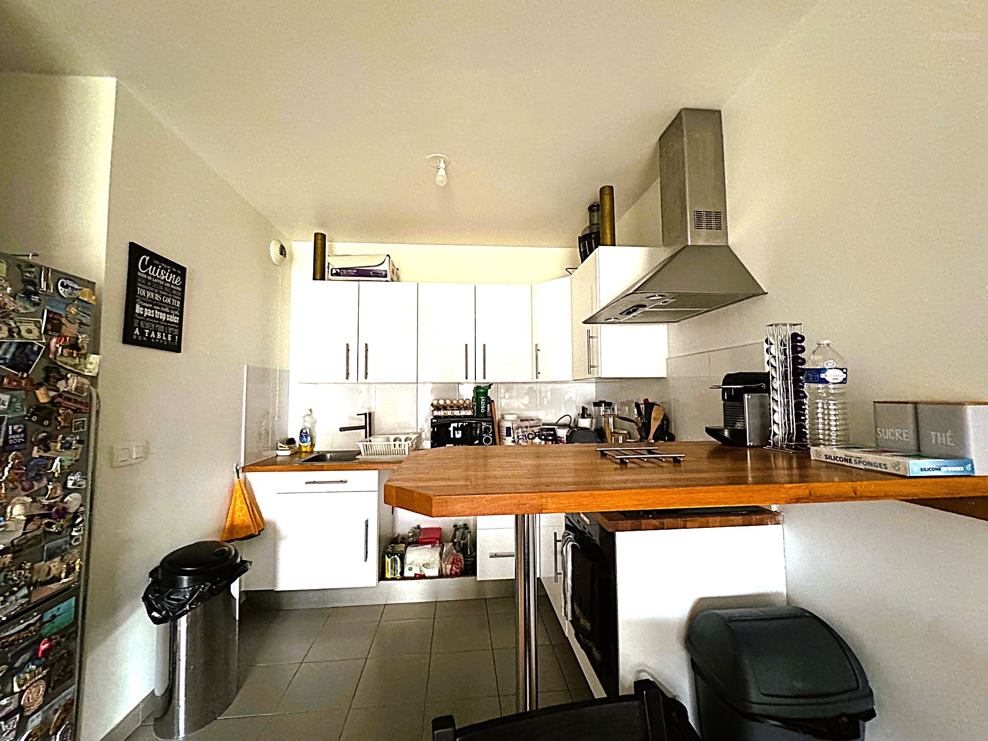 Appartement à vendre à Survilliers : cuisine avec plan de travail en bois et meubles blancs