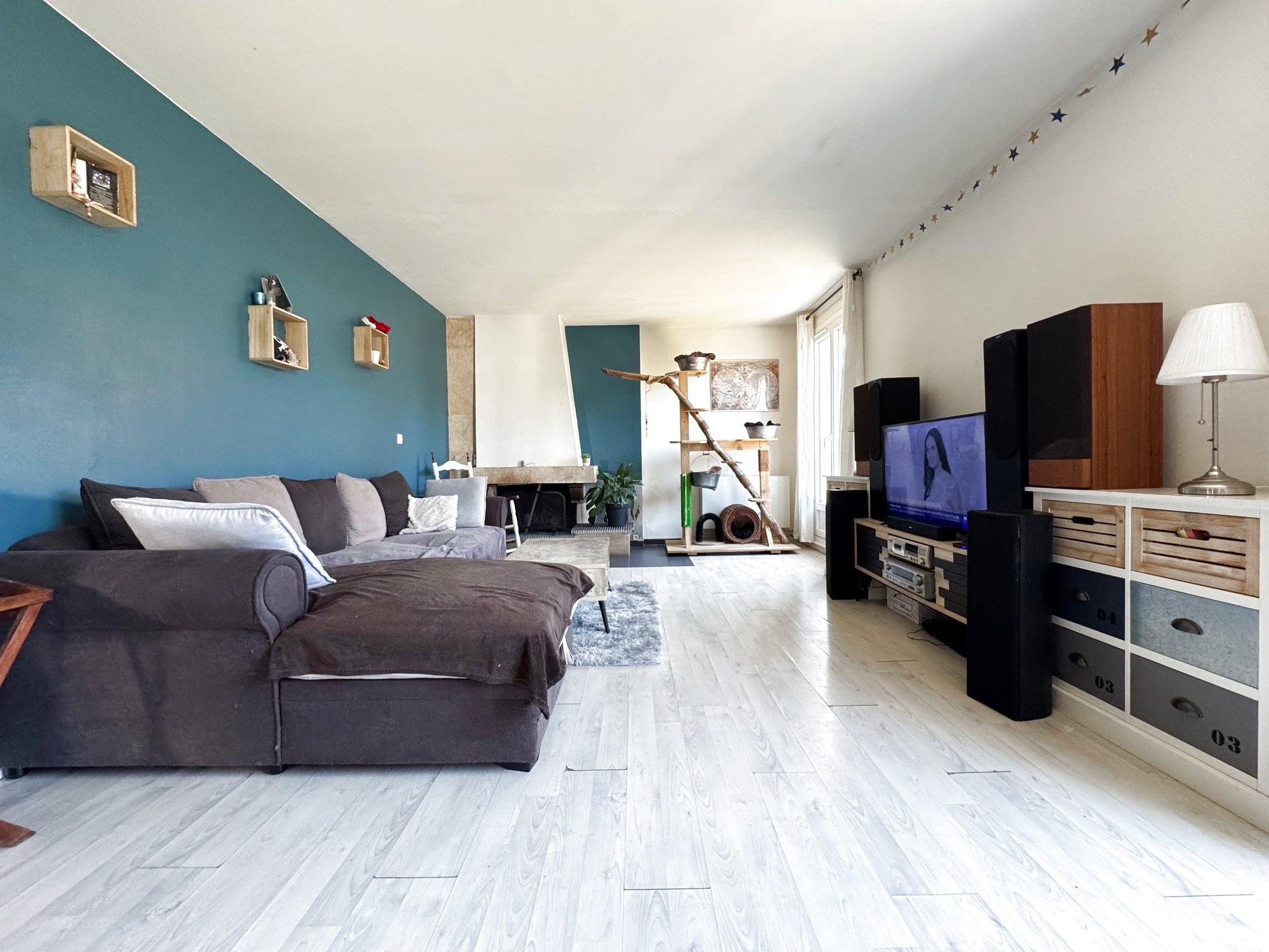 Maison à vendre à Plailly : salon avec canapé gris et un mur bleu décoré