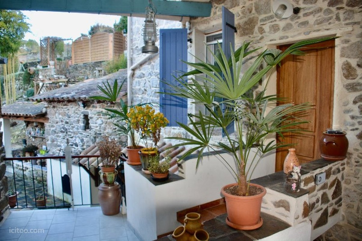 Maison à vendre à L'Estréchure : terrasse avec balustrade, plantes en pot et mur en pierre