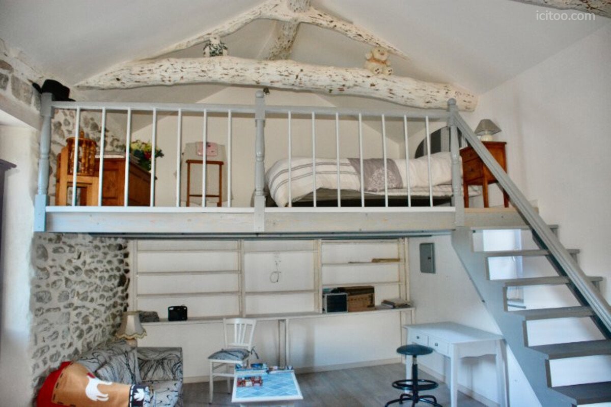 Maison à vendre à L'Estréchure : mezzanine avec lit, escalier, étagères et coin salon
