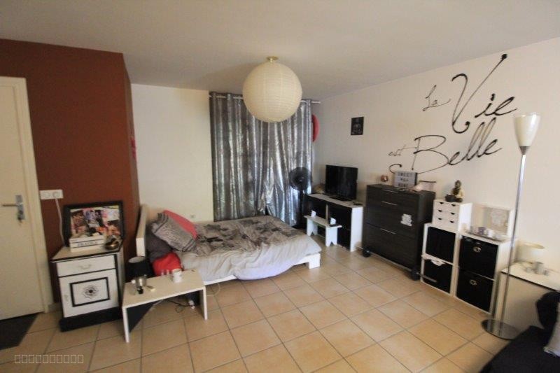 Studio à vendre à Ste clotilde : chambre avec lit, mur décoré et rideaux gris