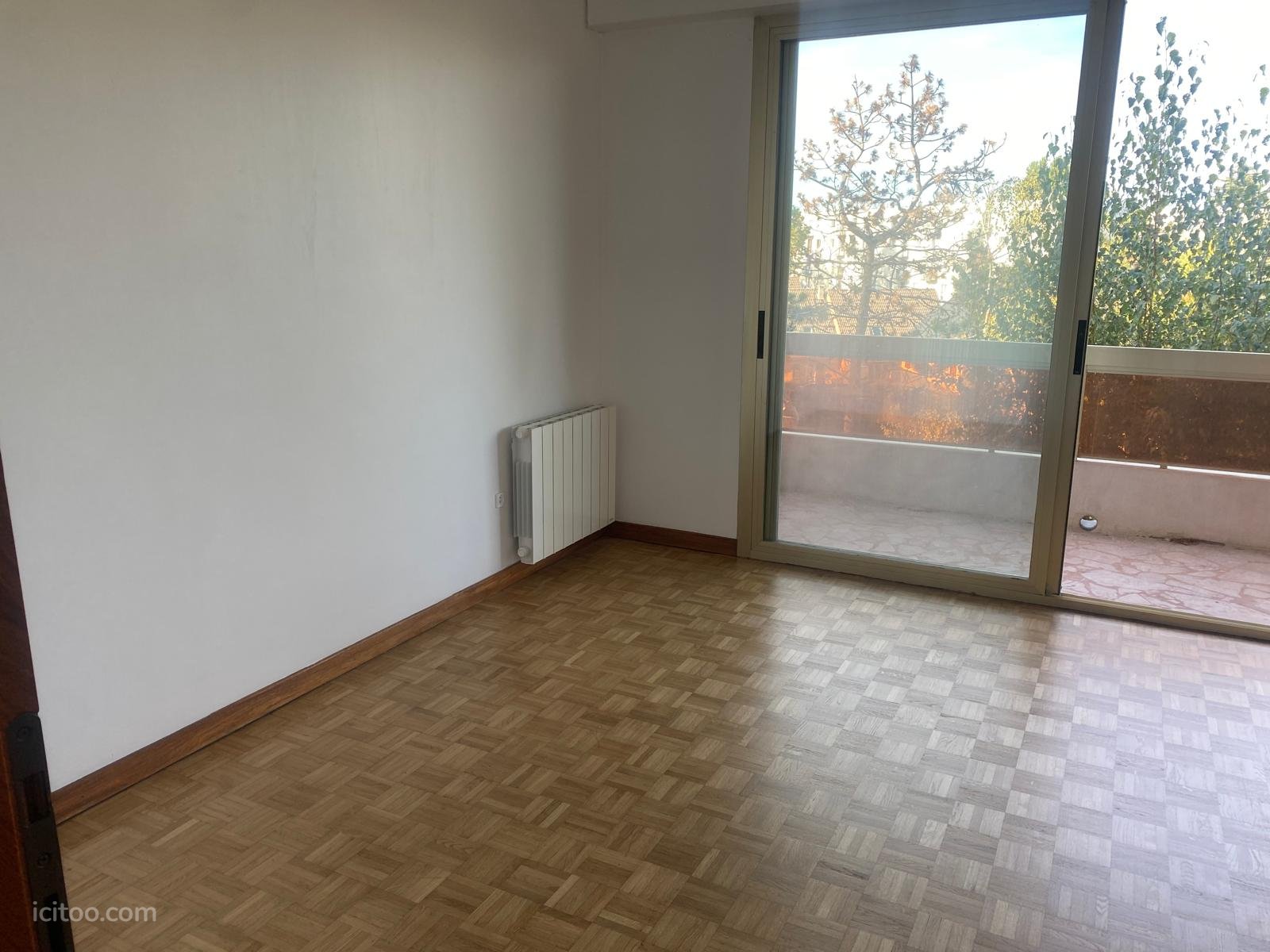 Appartement à louer à Domont : pièce vide avec radiateur blanc et baie vitrée