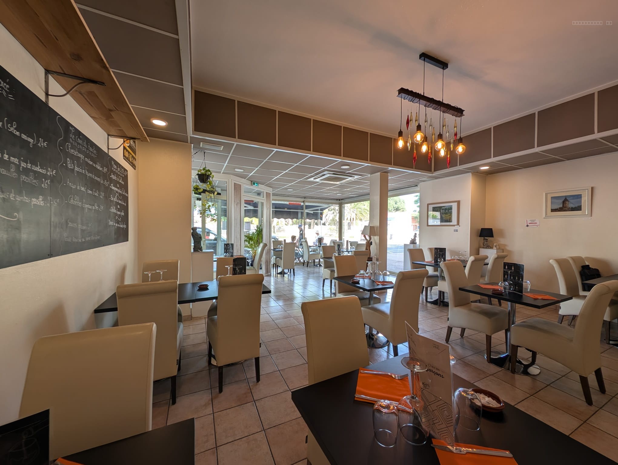 Fonds de commerce à vendre à Canet en roussillon : tables de restaurant avec chaises blanches et luminaires suspendus
