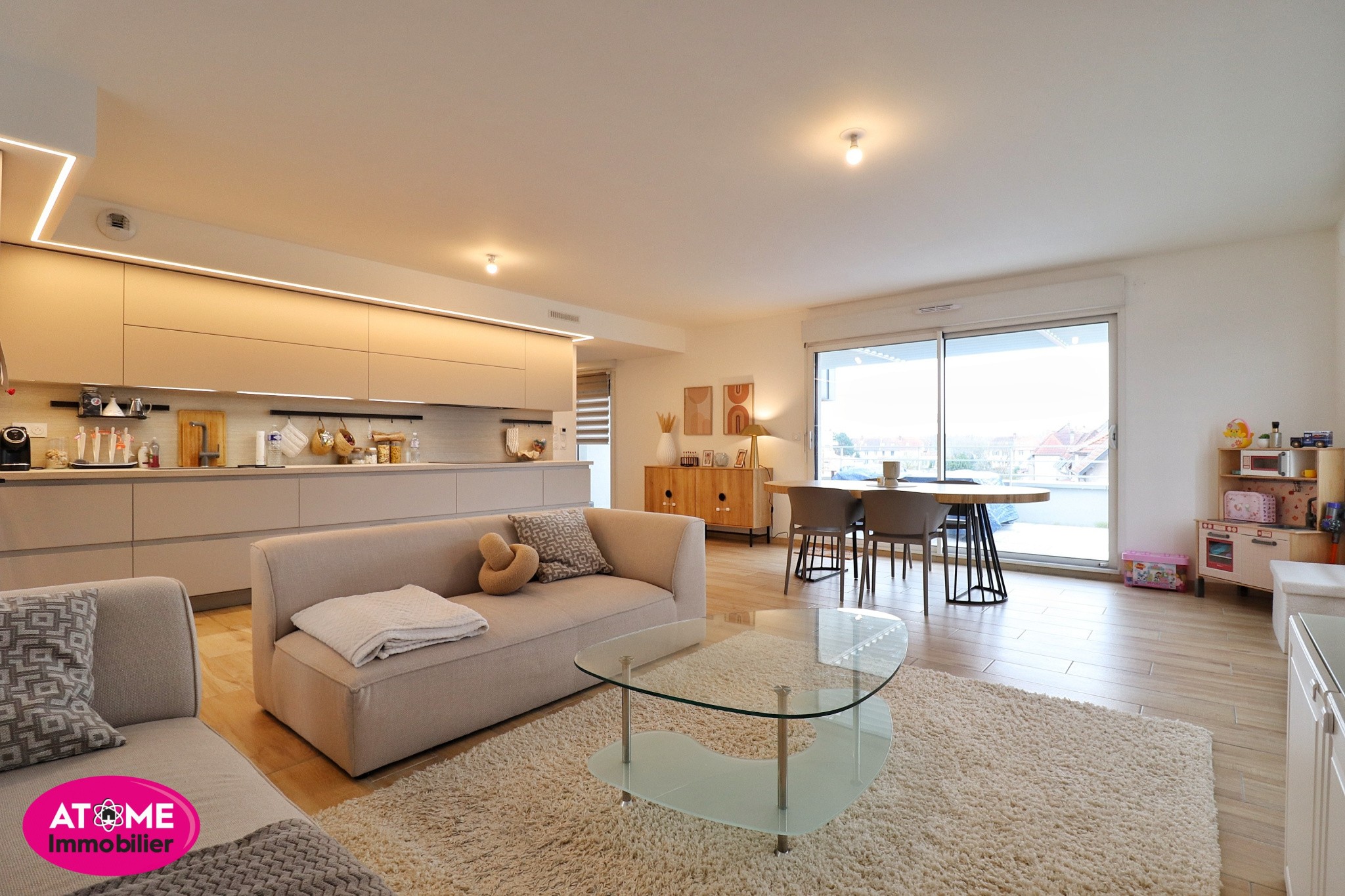 Appartement à vendre à Terville : canapé beige, table ronde et grande baie vitrée