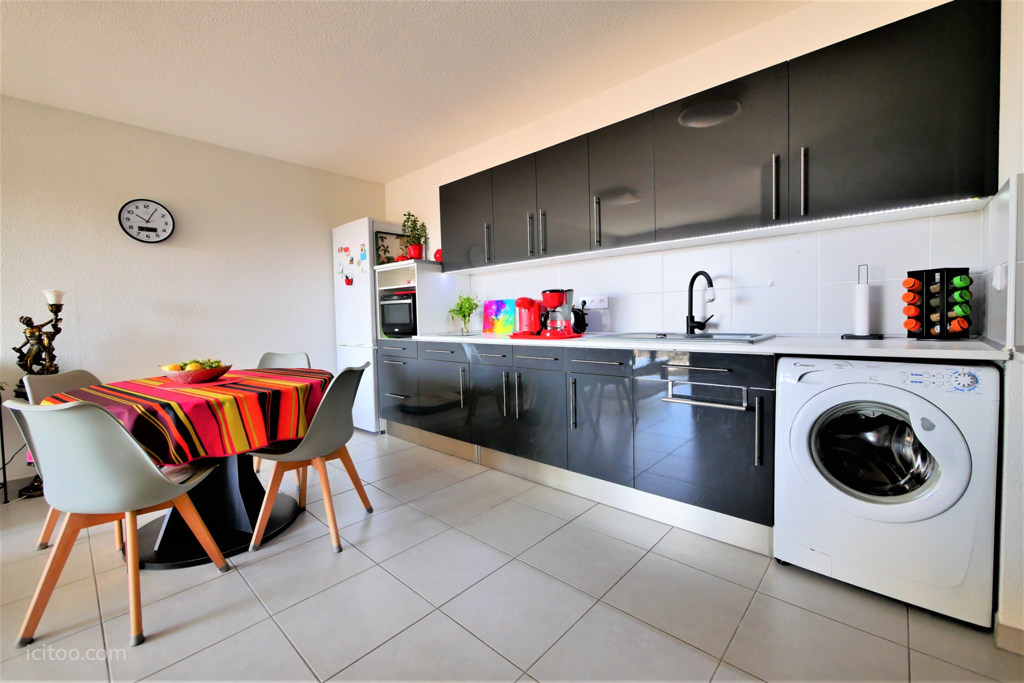 Appartement à vendre à Saint-Jean-de-Védas : cuisine avec meubles noirs et table à manger colorée