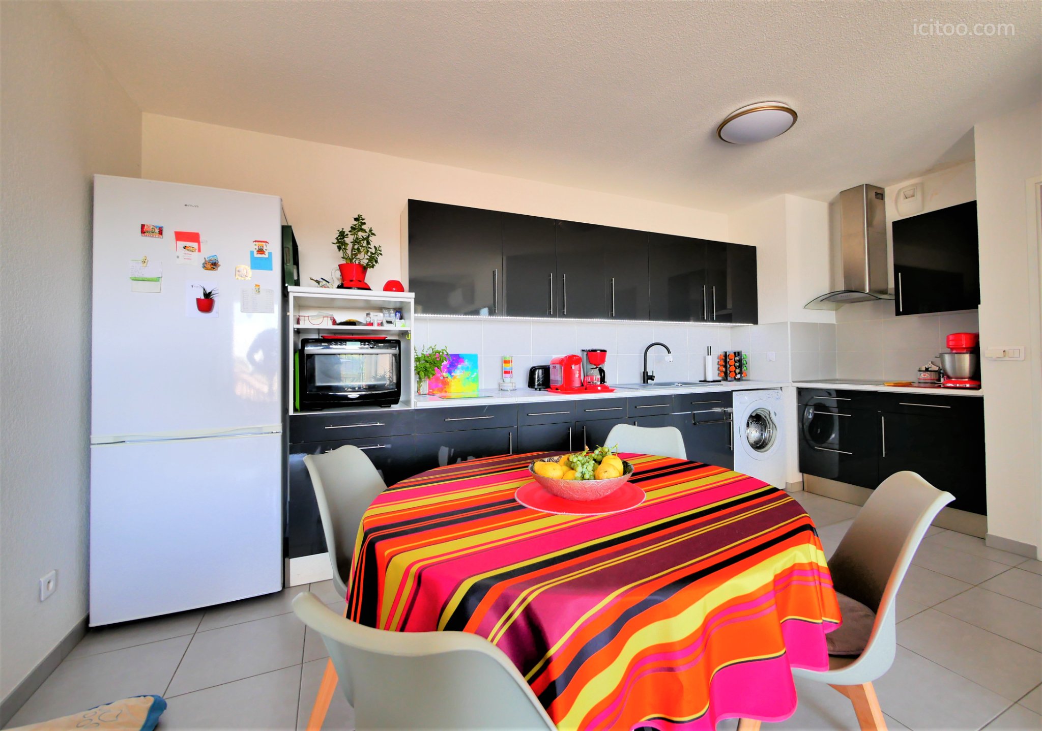Appartement à vendre à Saint-Jean-de-Védas : cuisine ouverte avec réfrigérateur blanc et table ronde