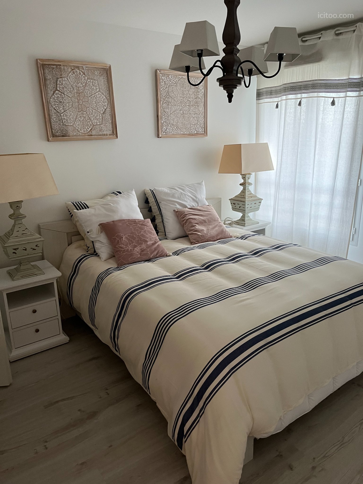 Appartement à vendre à Les Sables-d'Olonne : lit double avec couette rayée, tables de chevet et lampes