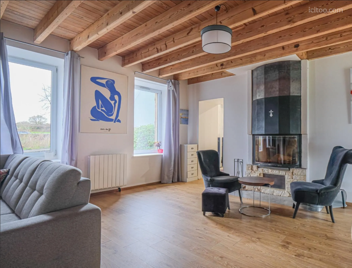 Maison à vendre à Fierville-les-Mines : salon avec cheminée moderne et fauteuils gris