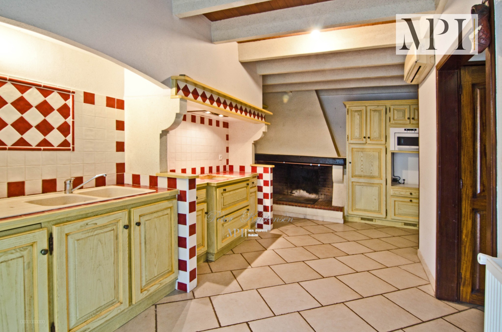 Maison à vendre à Trausse : cuisine avec meubles en bois et cheminée au fond