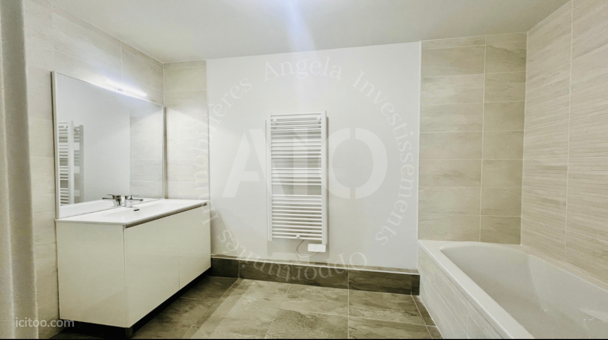 Appartement à vendre à Fontaines-sur-Saône : salle de bain avec baignoire, meuble vasque et radiateur