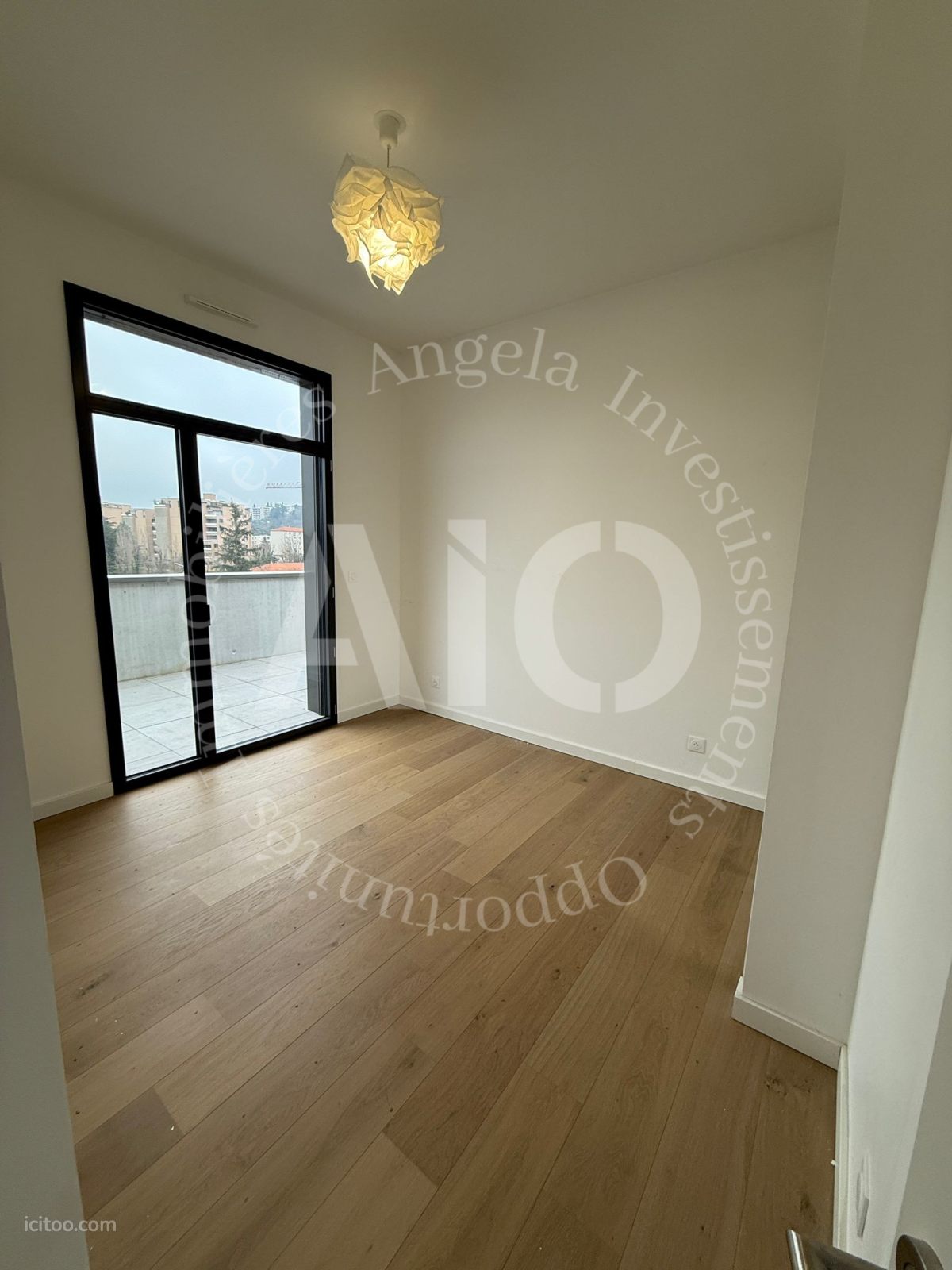 Appartement à vendre à Tassin-la-Demi-Lune : chambre vide avec parquet clair et baie vitrée