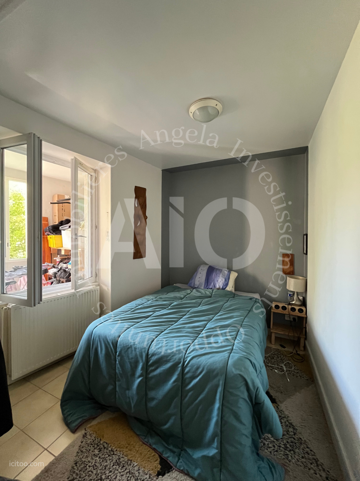 Appartement à vendre à Vindry-sur-Turdine : chambre avec lit recouvert d'une couette bleue et fenêtre